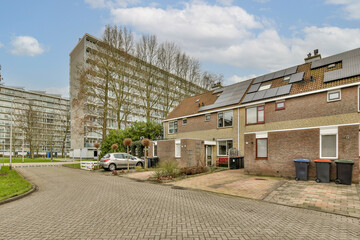 an empty street in the middle of a residential area with cars parked on both sides and buildings to the side