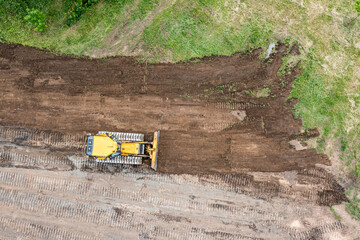 heavy construction machine is leveling the land. bulldozer is moving and flattening soil. aerial...