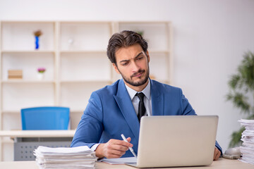 Young male employee and too much work in the office