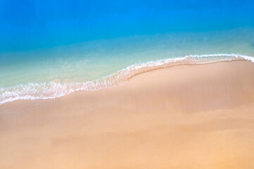 Aerial view beach sand background for summer vacation concept. Beach nature and summer seawater with sunlight light sandy beach Sparkling sea water contrast with the blue sky.