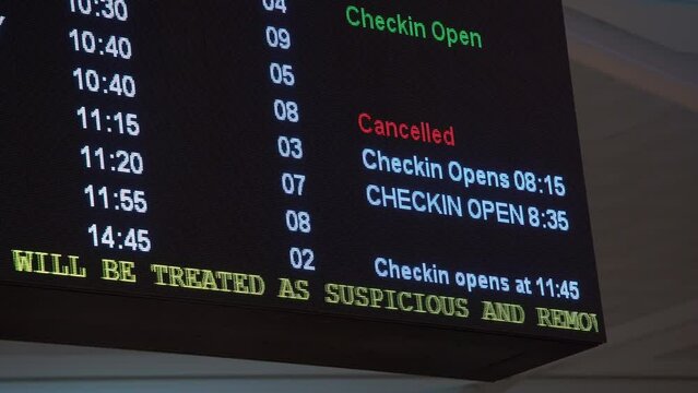 Airlines departure time schedules displayed on the billboard at the International Airport, check-in gates open, flight cancelled, handheld motion close up shot.