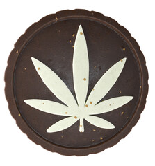 A flat round chocolate brownie with a cannabis leaf shape made of white chocolate