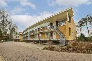 a building with stairs leading up to the top floor and two stories on the upper level, surrounded by trees