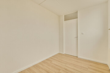 an empty room with white walls and wood flooring the door is open on the right side of the room