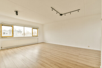 an empty room with wood flooring and large windows in the corner is very clean, but it's hard to see how