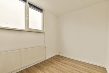 an empty room with white walls and wood flooring on the right side, there is a rad window
