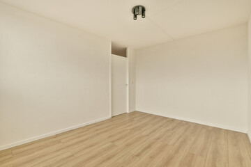 Fototapeta na wymiar an empty room with white walls and wood flooring on the right side, there is a door in the corner