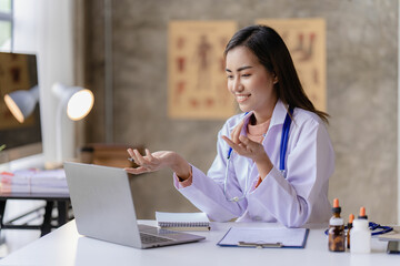 Asian female doctor meeting online speaking at laptop computer working in online clinic to help...