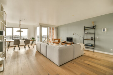 a living room with wood flooring and white walls in the center of the room is an open kitchen area