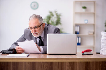 Old male employee working in the office