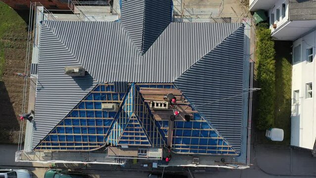 workers are putting on  new roof and tearing down old chimney, aerial view

