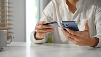 Man hand holding credit card and mobile phone making orders via internet or transaction on mobile banking application