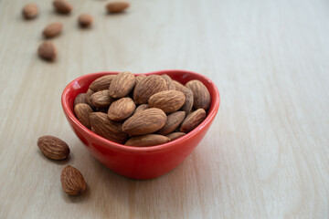 Almond nut organic healthy snack vegan vegetarian food, Almonds and Nutcracker. Tasty organic almond nuts snack fruit peeled roasted in heart ceramic bowl on wooden table, front view, copy space.
