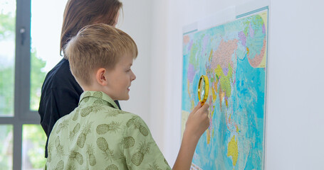 Boy and girl is playing in travelers and seeking country on the map