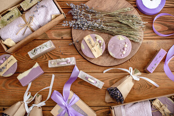 Fototapeta na wymiar Fragrant lavender bouquets wrapped in craft paper with ribbon, natural soap and gift boxes on a wooden table. Concept of packing handmade presents
