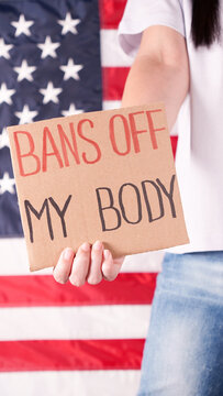 Woman Holding A Sign Bans Off My Body American Flag On Background. Protest Against Anti Abortion Law. Women's Strike. Womens Rights Freedom.