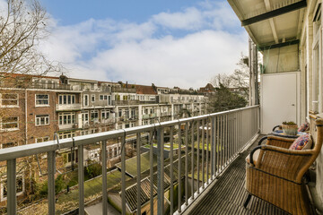 a balcony with a chair and some buildings in the background, on a sunny day that's just overcast