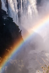 Telephoto shot of a rainbow being cast in front of the water thundering down victoria falls, in Zimbabwe.