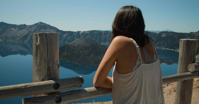 Girl looking out at lake island surrounded by mountains