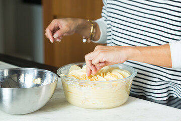 Woman hands putting apples while cooking apple pie