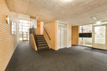 an empty living room with stairs leading up to the second floor and large windows in the room is very clean