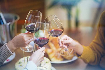 Cheerful friends enjoying home Birthday holiday party. Asian Friends cheering drinking red wine celebrating Christmas or New Year party