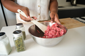 Close up of cuban woman hands mixing raw minced beef and garlic to prepare cuban style stuffed...