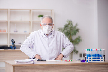 Old male chemist working at the lab