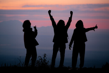 Silhouette of three women with sunrise on the background