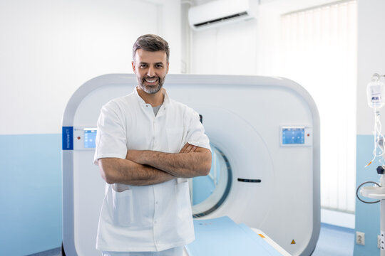 Confident male doctor oncology in magnetic resonance imaging or computed tomography room of a modern hospital.
