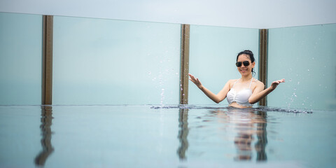 Portrait of a young smiling beautiful woman wearing white swimsuit and goggles while enjoying and relaxing in a swimming pool
