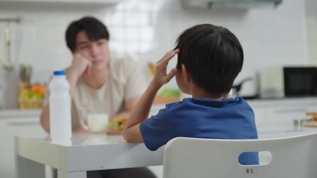 Asian single father talking and teaching son about the problem of children addicted to games on the table in the kitchen spend the holidays together