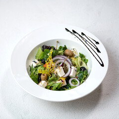 Salad with fresh vegetables, olives and feta in white plate. Healthy lifestyle. Mediterranean Kitchen. Light dinner. White background. View from above. Copy space. 