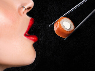 Sushi roll, glamorous woman with red lipstick eating sushi, close-up black background horizontal...