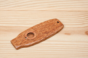 Kazoo is a musical wind instrument made of wood, filmed on a wooden surface.