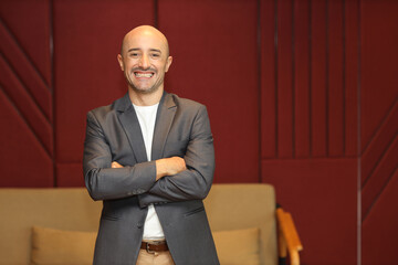 Portrait of attractive and handsome caucasian businessman in suit standing and crossing arms while looking away with confident happy face in modern office. Success business and technology concept