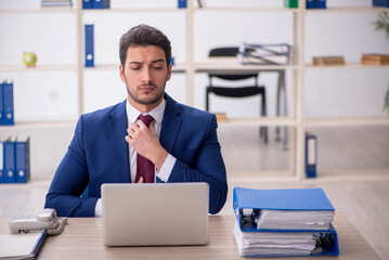 Young male employee and too much work in the office