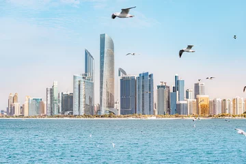 Foto op Canvas Marvel at the towering skyscrapers of Abu Dhabi, and flock of seagulls flying by © EdNurg