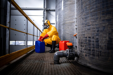 Industrial chemicals production. Experienced worker in protection suit, gas mask, gloves and boots...