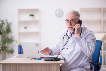 Old male doctor in telemedicine concept