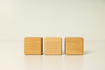 Three wooden cubes on white table, close up