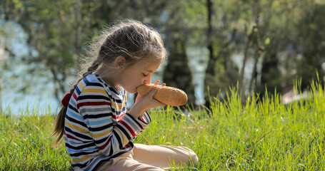 Girl eating a hot dog on the grass in the park