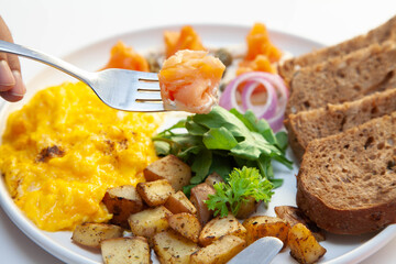 Smoked salmon with dill cream capers and scrambled eggs with rye bread and veggies.
