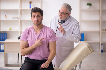 Fototapeta premium Young male patient visiting old male doctor