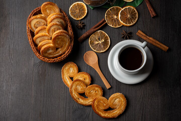Overhead view of puff pastry sweets with cup of coffee, dried oranges and cinnamon sticks, horizontal, with copy space