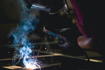 Industry worker welding iron pieces at work
