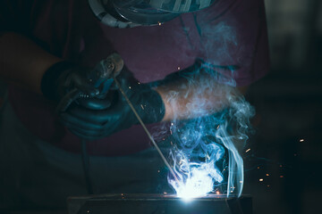 Industry worker welding iron pieces at work