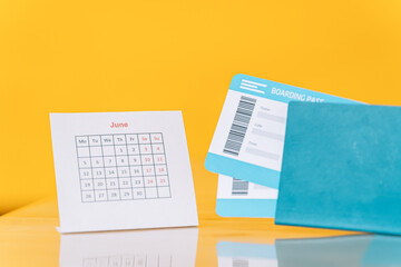 Obraz premium Air tickets in the passport next to the June calendar against yellow background.