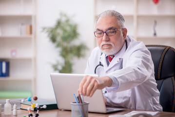 Fototapeta premium Old male doctor working in the clinic