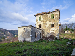 Obraz premium Old, abandoned, prairie farmhouse with trees, grass and blue sky